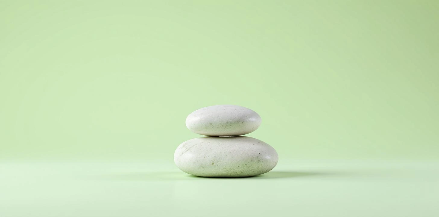 Zen stones stacked on green background representing meditation and relaxation for anxiety treatment